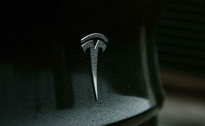 T Tesla logo on the back of a black car.