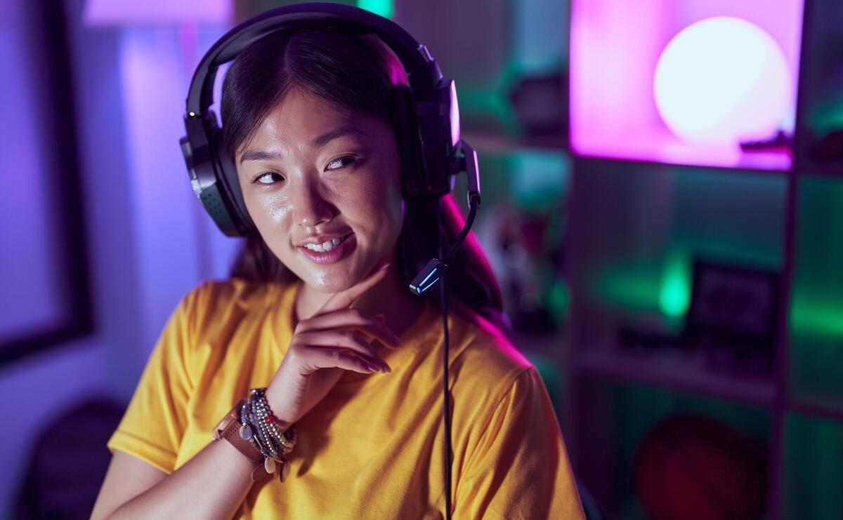 Chinese woman streamer smiling confident using headset at gaming room