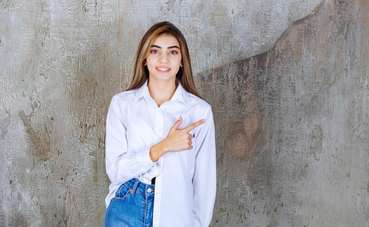 Portrait of young female model standing and pointing over marble