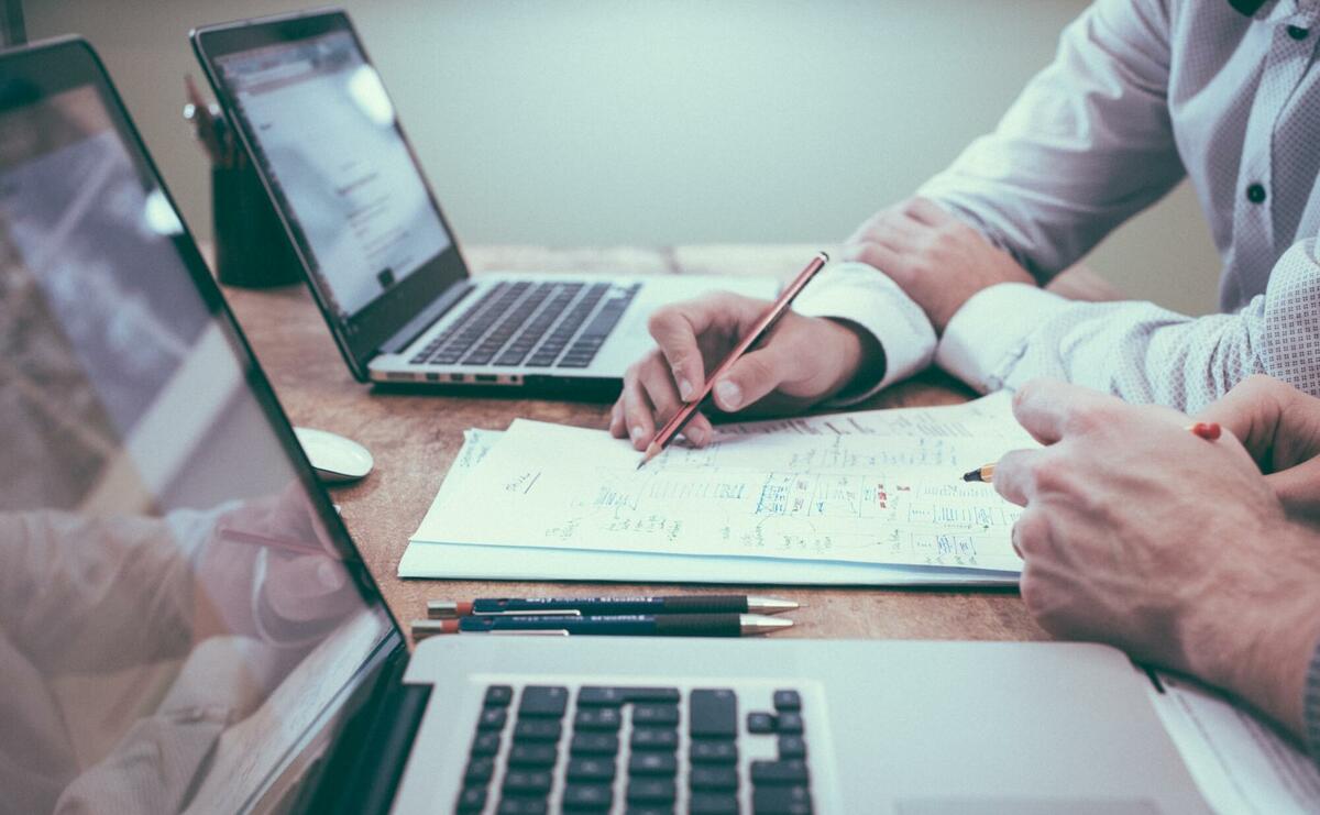 Person holding pencil near laptop computer.