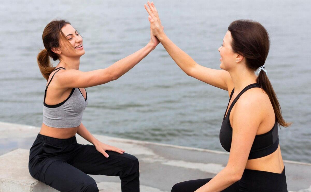 Side view of women high-fiving each other while exercising outdoors