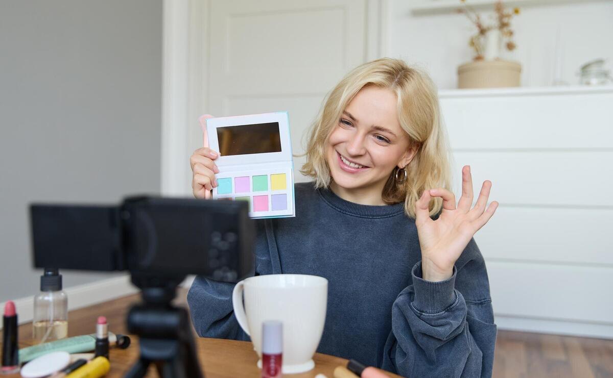 Portrait of beautiful smiling woman recording video in her room has camera on coffee table reviewing