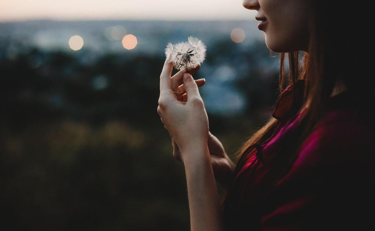 Female portrait. Nature. Pretty woman plays with dandelion stand