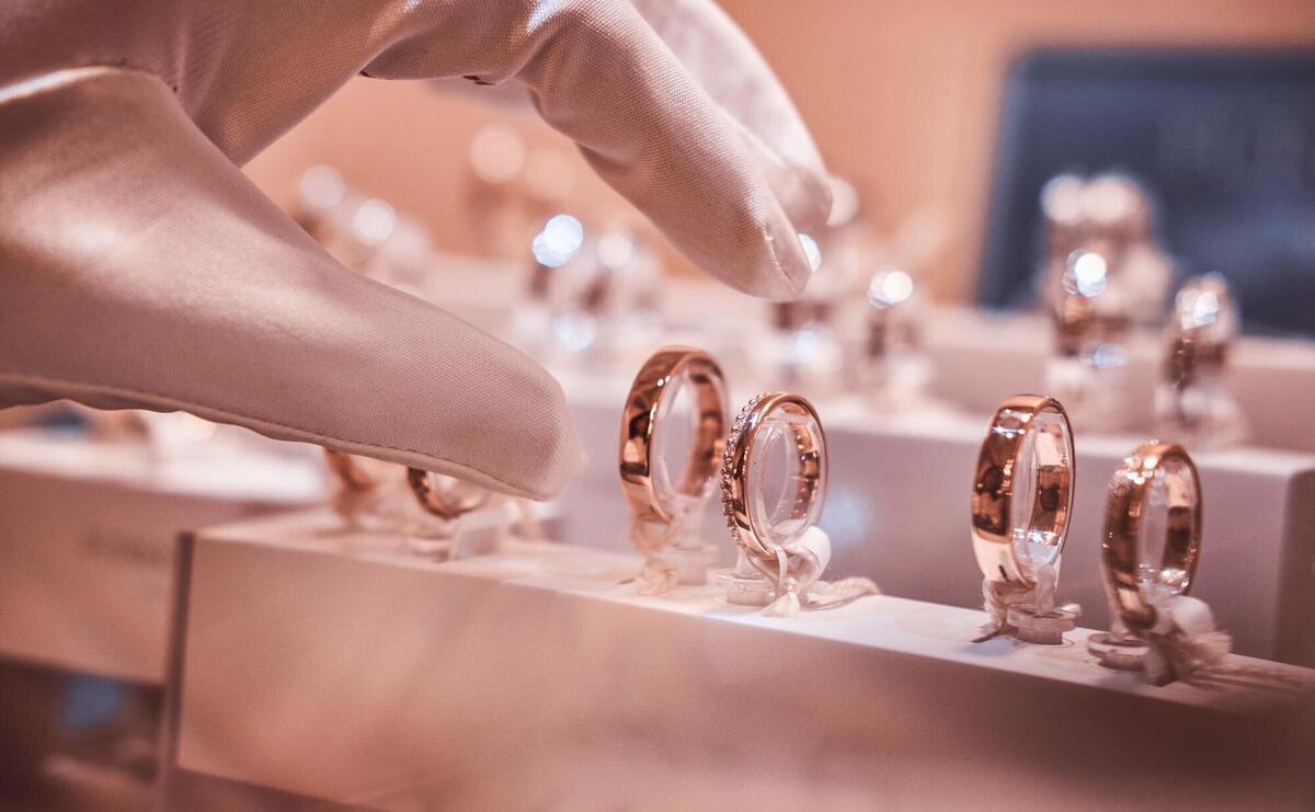 Hand in gloves takes to exclusive rings on the showcase of a luxury jewelry store