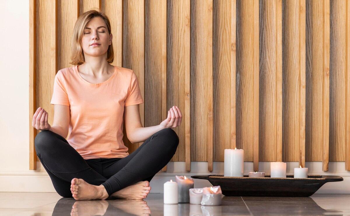 Full shot woman meditating with candles