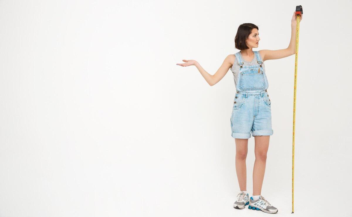 Full length portrait of woman measure herself with tape