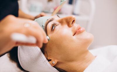 Cosmetologist applying mask on a face of client in a beauty salon