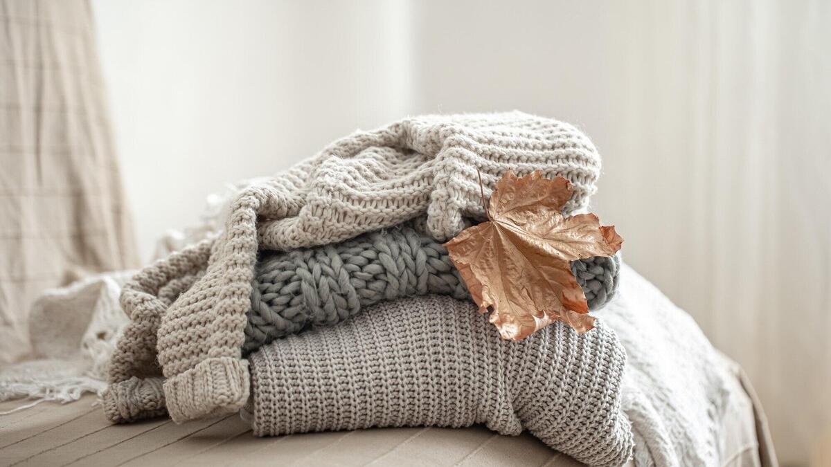 Close-up of a stack of knitted sweaters on a blurred background.