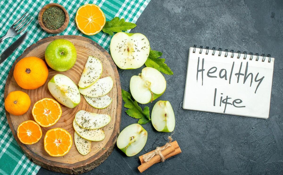 Top view cut apples and tangerines with dried mint powder on wood board cinnamon sticks on tablecloth