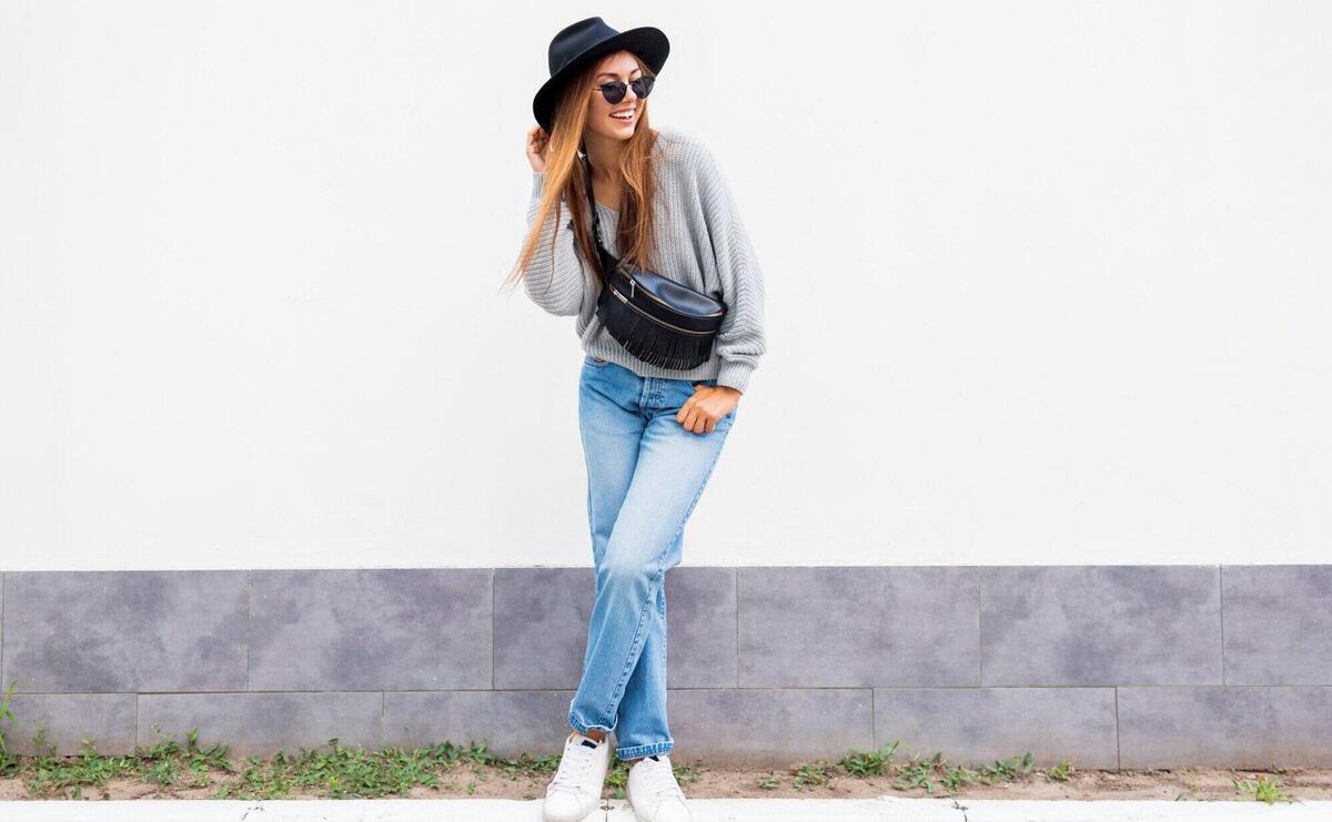 Successful  exited stylish girl with candid smile posing on white urban wall