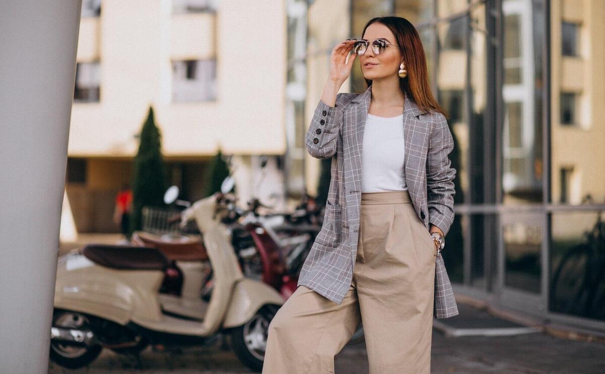 Young woman in suit standing by the scooter