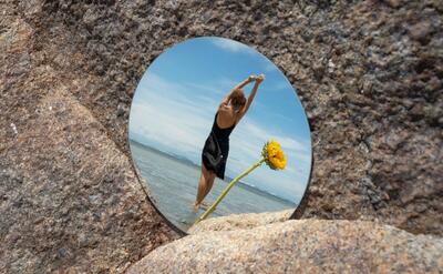 Woman posing with round mirror and flower