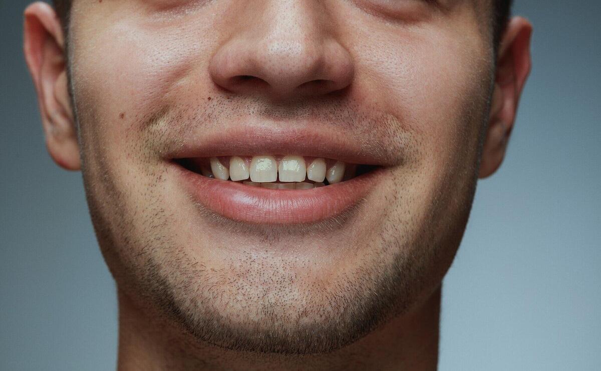 Close-up portrait of young man isolated on grey  background. Caucasian male model's face and lips.