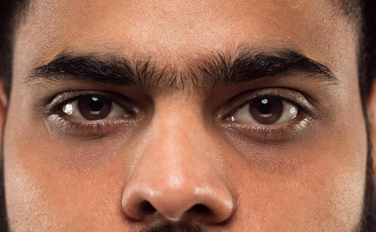 Close up portrait of young hindoo man's face with brown eyes looking right at camera