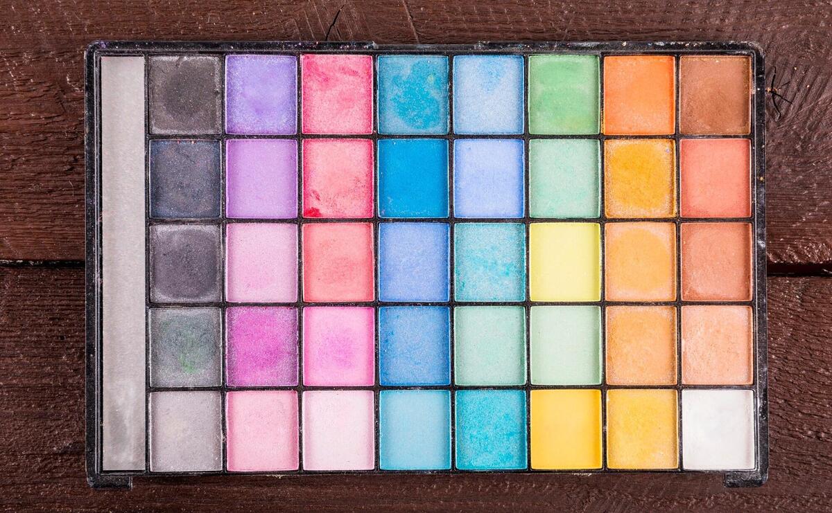 Overhead view of colorful eye shadow powder on wooden background