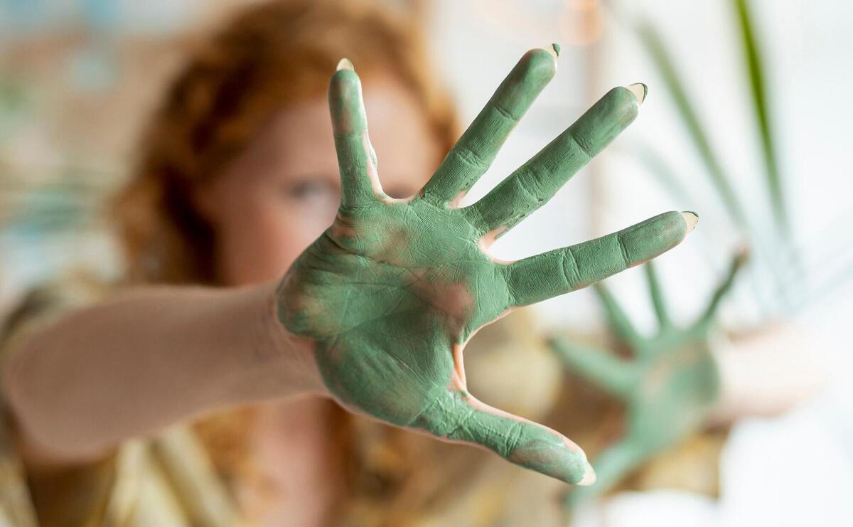 Close-up green paint on woman's palm