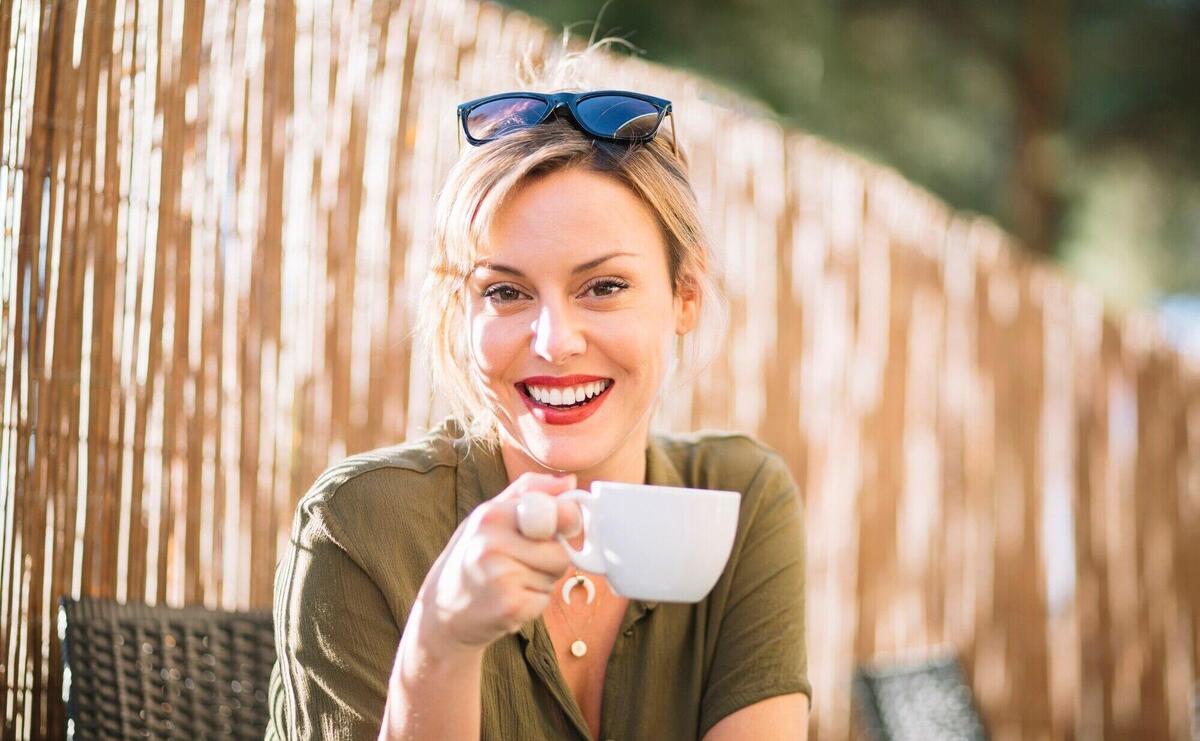 Cheerful woman with drink looking at camera